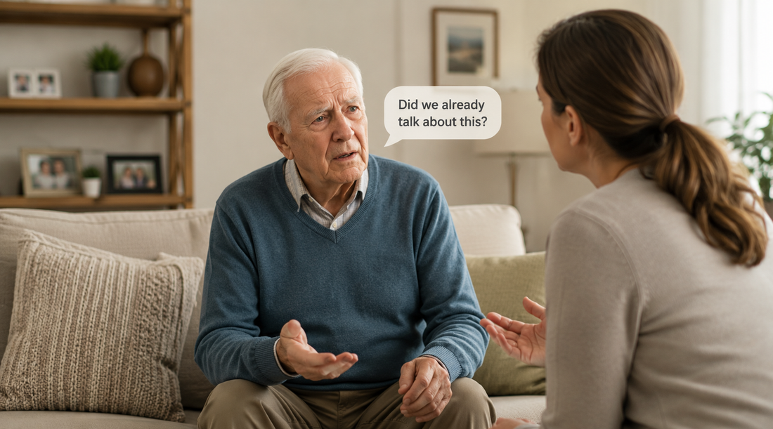 Older man having a conversation with a caregiver in a living room, illustrating a common dementia symptom of repeating the same questions or stories due to memory loss.