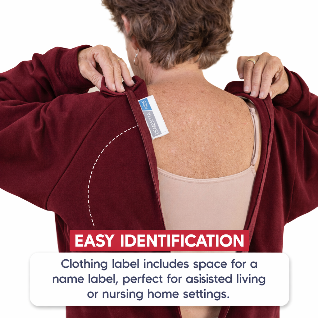 Person wearing a burgundy dementia jumpsuit with an attached label on the back, suitable for assisted living or nursing home settings.