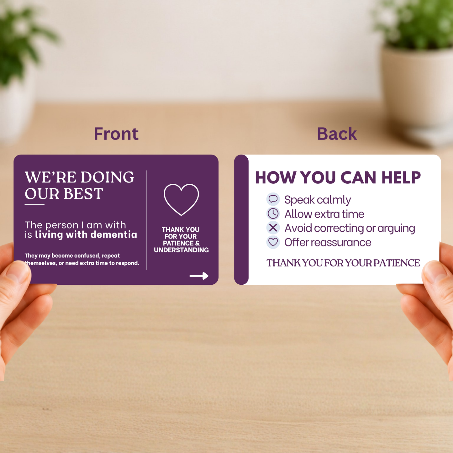 Two caregiver communication cards(back and front) held by hands, one purple with text and a heart symbol, the other white with instructions on a wooden surface.